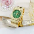 Close-up detail of a luxurious gold cuff watch featuring a striking green round dial design. - Gold Green