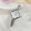 Detailopname van een klaverblad dameshorloge met sprankelende strass-steentjes en fijne band. - Zilverwit