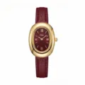 Primo piano di orologio al quarzo da donna con quadrante bordeaux e lunetta dorata. - Cassa Dorata Quadrante Rosso Cinturino Rosso