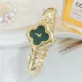 Close-up detail of the elegant green clover dial and gold-tone metal strap women watch closeup. - Green