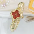 Detailed view of a luxury gold women watch with a striking red four-leaf clover dial. - Red