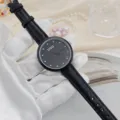 Detail view of the black dial quartz watch with rhinestone markers and leather strap. - Black