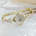 Close-up detail of luxury gold-tone women bracelet watch featuring star and moon charms. - White Dial Pink