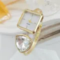 Nahaufnahme Detail der luxuriösen goldenen Quarzuhr als offener Armreif mit grossem Kristall. - Gold Weiß