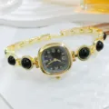 Primer plano detallado de reloj de pulsera dorado con esfera cuadrada negra y perlas. - Negro