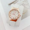 Gros plan d'une élégante montre à quartz en or rose avec lunette en cristal et bracelet blanc. - Blanc