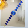 Detailansicht der goldenen Quarzarmbanduhr mit blauen Kristallen für elegante Damen. - Blau