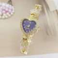 Nahaufnahme des Strass-Herz-Uhren-Details, goldenes Metallarmband und violettes Zifferblatt. - Goldblau