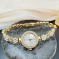 Elegant gold quartz watch for women with rhinestone bezel and floral bracelet links. - Watch Only Style / Gold White