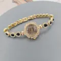 Primer plano del detalle de reloj de cuarzo dorado para mujer, diseño elegante de estrás y piedra. - Dorado Negro