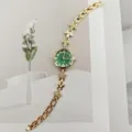 Nahaufnahme der goldenen Damenuhr mit grünem Zifferblatt und Kristallblattarmband. - Gold Grün