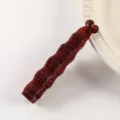 Dark red plastic banana hair clip closeup, irregular wavy design, minimalist ponytail accessory. - Glossy Jelly Red