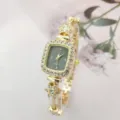 Detaillierte Nahaufnahme der luxuriösen goldenen quadratischen Strassuhr mit Blumenarmband. - Goldenes Gehäuse Schwarzes Zifferblatt