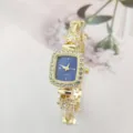 Elegante quadratische Quarzdamenuhr mit funkelnden Strasssteinen und Blütenarmband im Detail. - Goldenes Gehäuse Blaues Zifferblatt