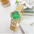 Dettaglio orologio trifoglio strass oro con quadrante verde e maglie bracciale scintillanti. - Cassa Oro Quadrante Verde