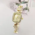 Nahaufnahme der goldenen Damenuhr mit Quarzwerk, glitzernden Strasssteinen und Blumenband. - Goldenes Gehäuse Goldener Zifferblatt