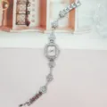 Detaillierte Nahaufnahme des quadratischen Strass-Zifferblatts und floralen Armbanddetails. - Silbernes Gehäuse Rosa Zifferblatt