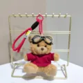Cute plush pilot bear keychain with goggles, red shirt, and lanyard. Perfect bag charm. - Brown Bear in Red Clothes