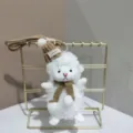 Detailed close-up of the cute white plush lamb keychain featuring a brown knitted hat and scarf. - 15cm / Brown