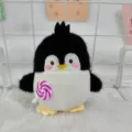 Cute penguin plush toy close-up detail, holding a pink lollipop, soft plush material. - Ball Chain / Black