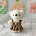 Detail view of cute white plush bear keychain wearing brown plaid strap dress accessory. - White with Grey Skirt