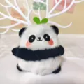Niedlicher flauschiger Panda Plüsch Anhänger Nahaufnahme mit grünem Spross und Dekoration. - Gras