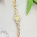 Close-up detail of the elegant gold rhinestone quartz watch dial and sparkling bracelet band. - Gold