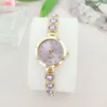 Nahaufnahme Luxus Damen Quarz Uhr mit lila Steinen und funkelndem Armband Detail. - Gold Violett