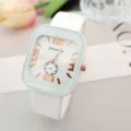 Détail de montre carrée en silicone élégante avec cadran blanc et chiffres en or rose. - Blanc