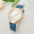 Elegant rhinestone bezel and blue leather strap watch detail, featuring a clear dial with numbers. - Blue