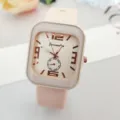 Gros plan détaillé d'une montre à quartz carrée avec bracelet en silicone rose et chiffres. - Beige