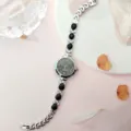 Nahaufnahme der Damen Quarzuhr Armband mit schwarzen Tropfensteinen und funkelnden Kristalldetails. - Silberschwarz