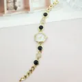 Detaillierte Nahaufnahme der eleganten goldenen Damen Quarz Armbanduhr mit schwarzen Steinen. - Gold Schwarz