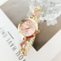 Close-up view of gold-tone quartz watch with pink dial and sparkling pink gemstone bracelet. - Pink