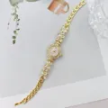 Goldene Damen Quarzuhr mit glitzerndem Strass Blumen Armband Design fuer elegante Anlaesse. - Gold Weiß