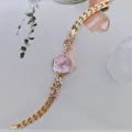 Nahaufnahme der goldenen Quarzuhr mit rosa Zifferblatt und Strass-Schmetterling-Armband. - Gold Violett