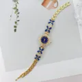 Elegante goldene Damen Quarz Armbanduhr mit blauen Strass Blüten und filigranem Armband Stil. - Goldblau