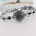 Silberne Damenuhr mit Quarzwerk, schwarzen Schmucksteinen und funkelnden Strasssteinen. - Silber Schwarz