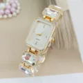 Close-up detail shot of the elegant rectangular crystal quartz women watch strap links. - Gold White