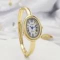 Elegant gold oval quartz bangle watch for women featuring Roman numerals and blue hands. - Gold Case White Dial