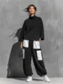 Detailed view of stylish black cargo pants featuring white contrast pockets and top. - S / Top And Bottom / Black