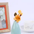Artificial flower detail view, small yellow floral arrangement in a light blue ceramic vase. - Style 7