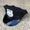 Vista detallada de una gorra de policía negra para disfraces con insignia bordada y visera. - Talla única / Gorra octogonal negra con etiqueta de cuero