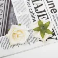 Detailopname van witte kunstrozen bloemhoofdjes met de voorkant en groene kelkbladen. - Stijl 10
