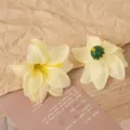 Nahaufnahme künstlicher gelber Lilienblütenköpfe mit grünem Boden für Bastelarbeiten. - Gelb