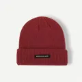 Close-up detail of the dark red knitted beanie showcasing fine ribbed texture and woven label. - One Size / Burgundy