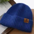 Detailansicht der blauen Strickmütze mit Lederaufnäher, warme Wintermütze für Damen und Herren. - Einheitsgröße / Blau