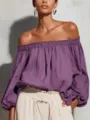 Vista dettagliata del top viola con spalle scoperte e maniche a lanterna lunghe ed eleganti. - Viola