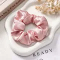 Detail van een roze sateen haarelastiekje op een witte schaal met droogbloemen decor - Roze