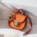 Mini llavero de bolso tipo silla de montar en cuero naranja con herrajes dorados. - Naranja